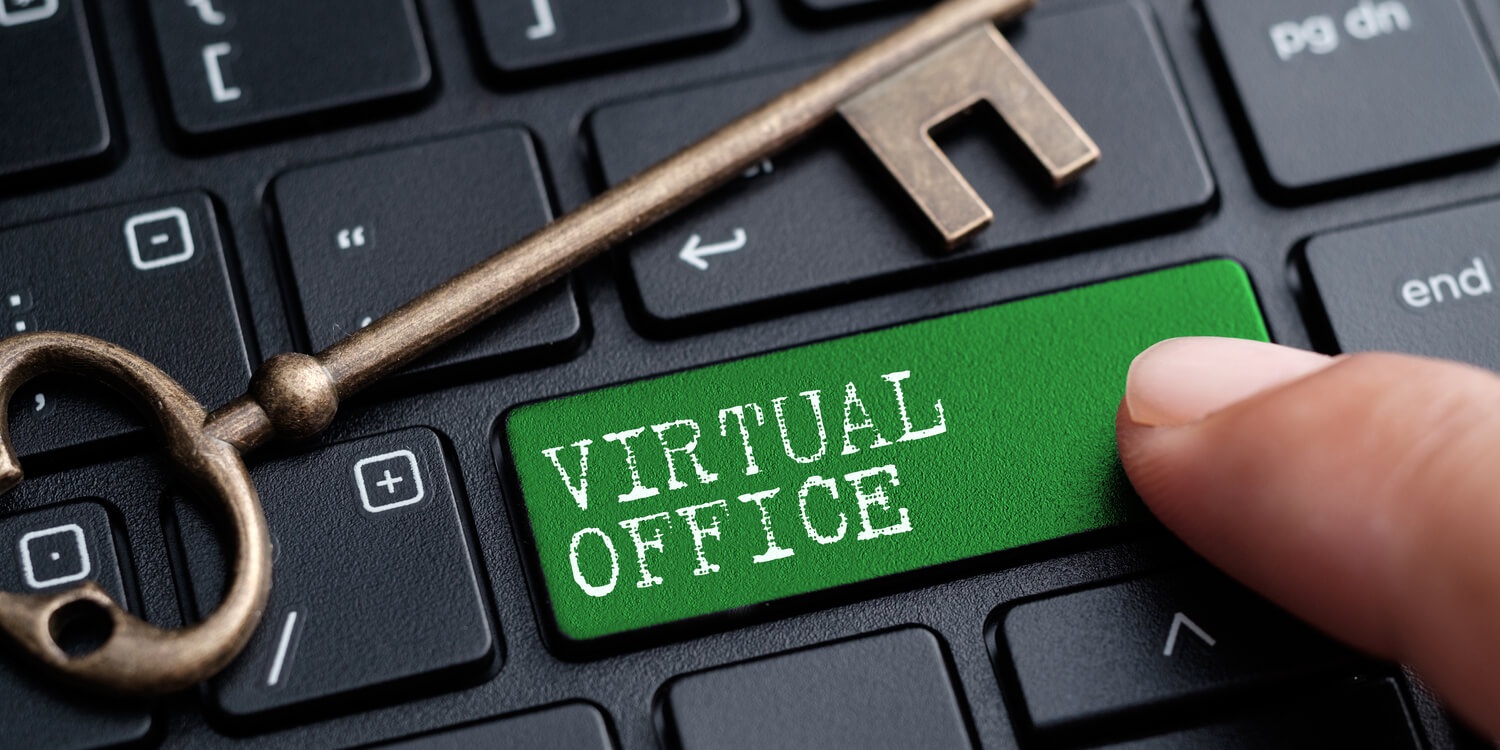 Black laptop keyboard with large green key labelled 'Virtual Office' and brass door key lying on keyboard.